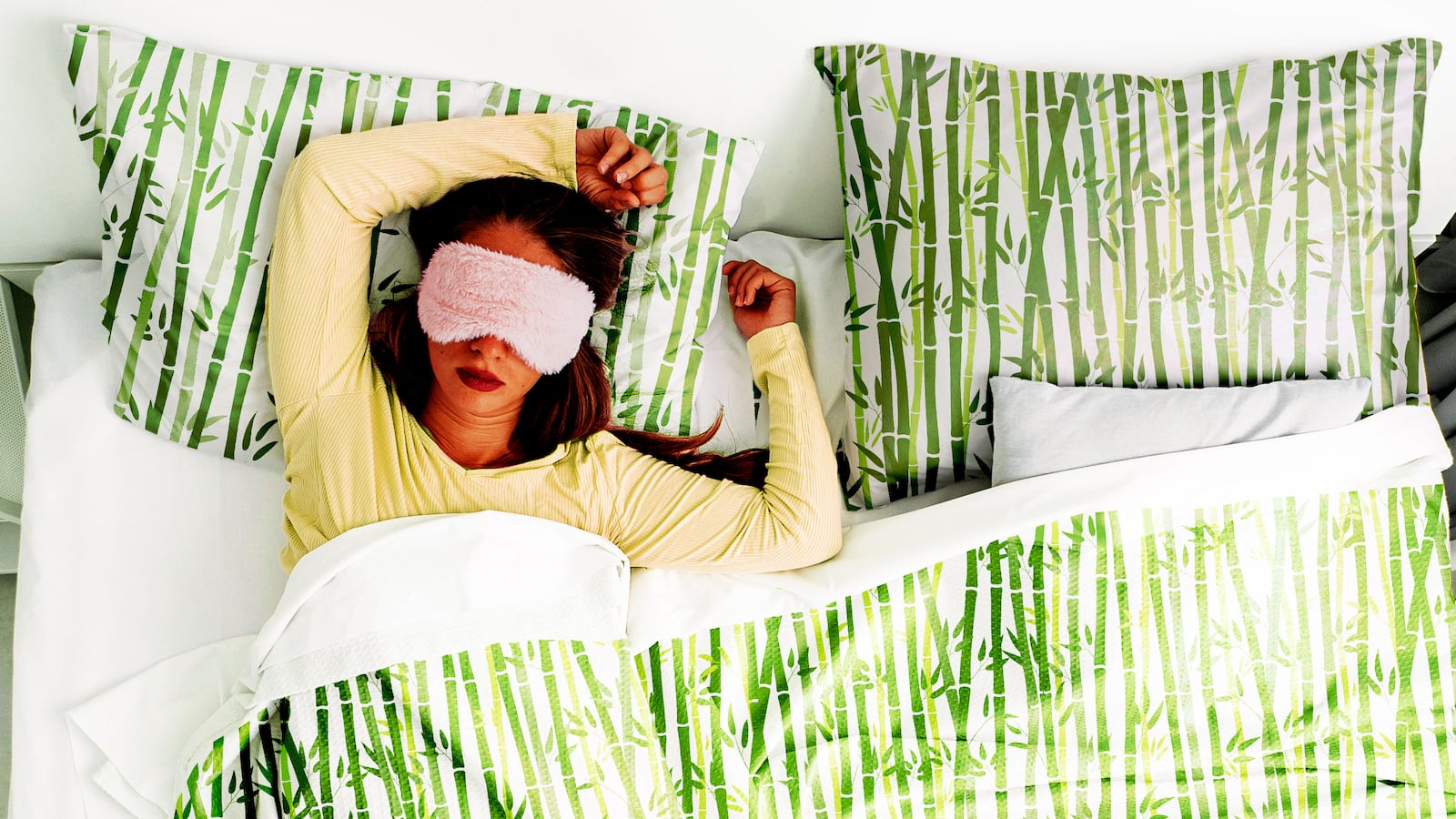 Woman laying in bed with sheets with bamboo patterns on it