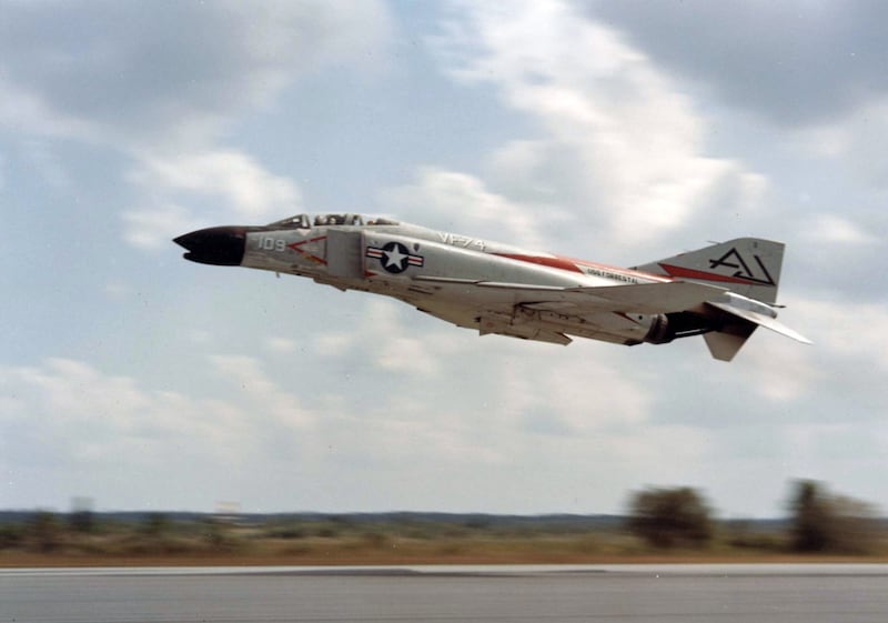 An F-4 fighter jet in flight close to either landing or take off. It is marked USS Forrestal