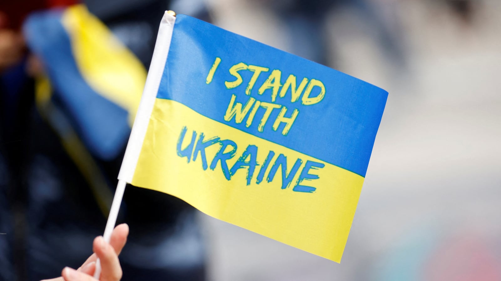 A person holds a Ukrainian flag as people attend a rally to mark the one-year anniversary of Russia’s invasion of Ukraine, in Paris, France, Feb. 25, 2023.