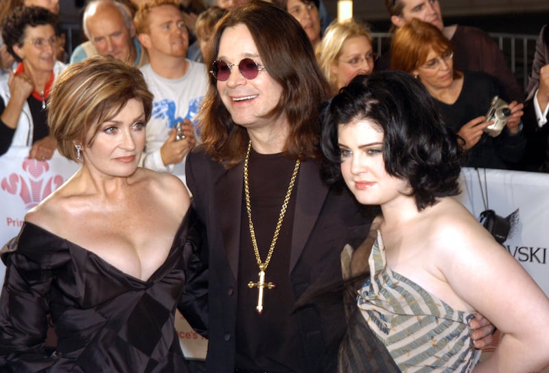 Ozzy Osbourne wears a rosary while posing with his wife, Sharon, and daughter, Kelly.