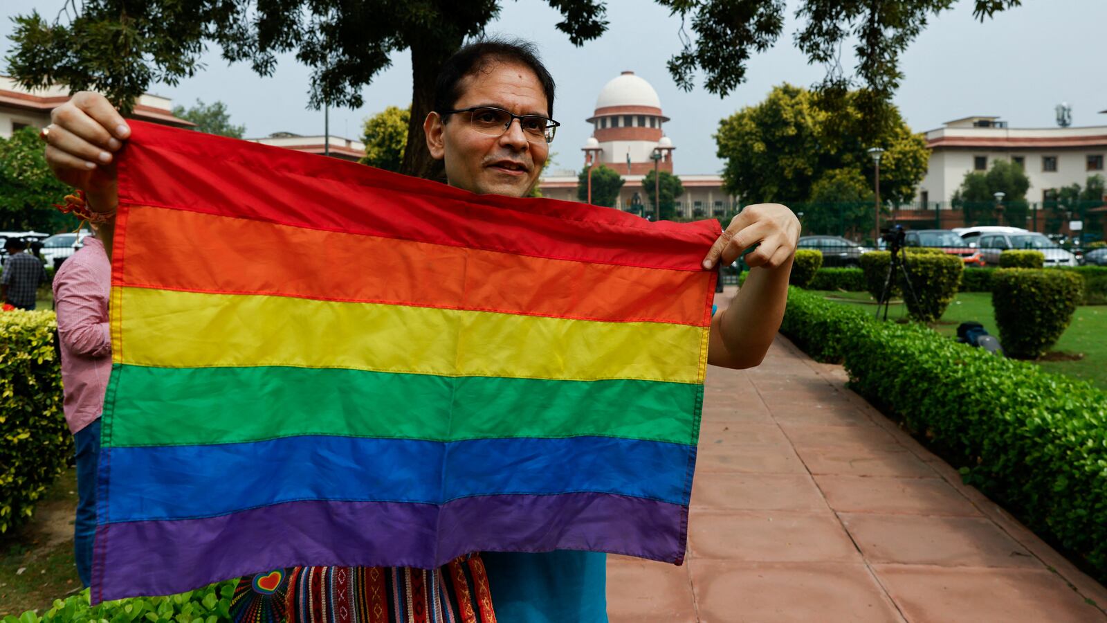 A writer and member of the LGBT community holds the pride flag while waiting to hear the judgement on same-sex marriage by the Supreme Court in New Delhi, India, Oct. 17, 2023.