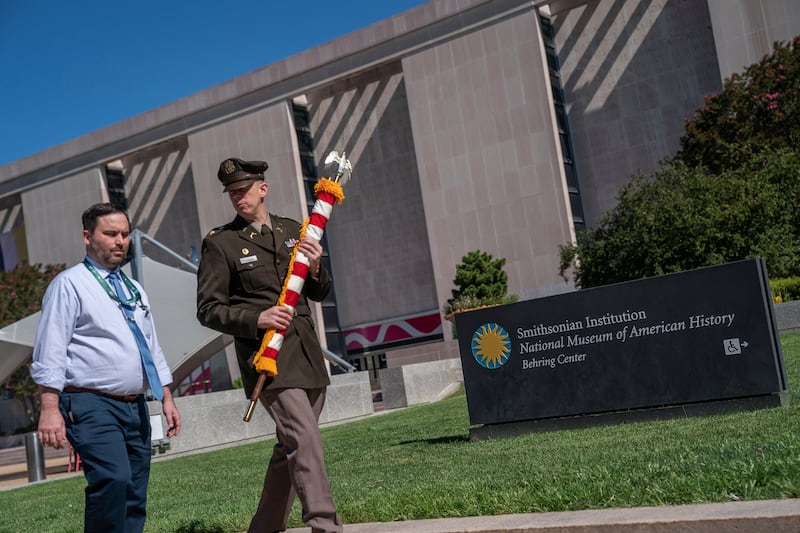 A member of the U.S. military carries an American flag near the Smithsonian National Museum of American History in Washington, D.C., U.S., July 30, 2026.