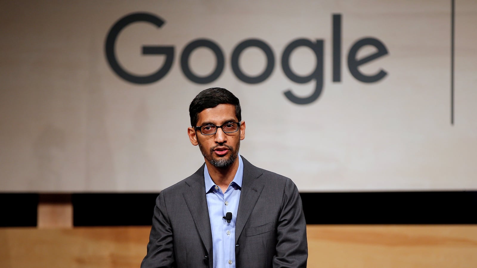 Sundarr Pichai speaks at a podium with a “Google” sign behind him.