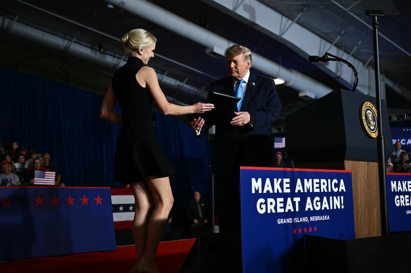 Executive assistant to US President Donald Trump, Natalie Harp, hands an executive order for US President Donald Trump to sign during a campaign rally at Pinnacle Bank Expo Center in Grand Island, Nebraska, on October 5, 2026.