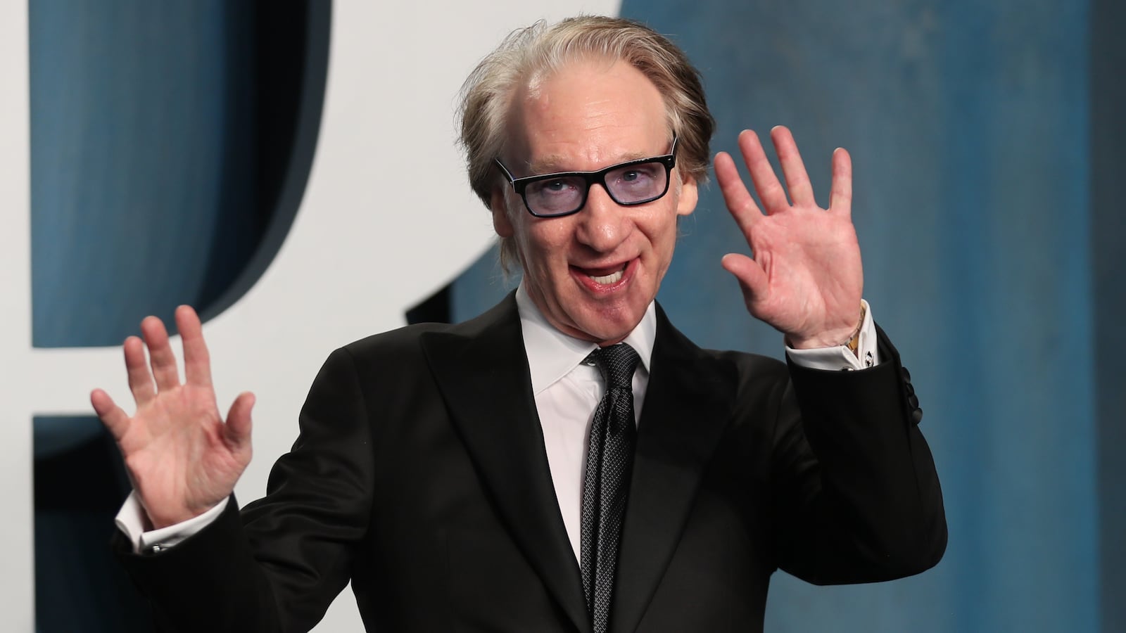 Bill Maher waves his hands while speaking on stage.