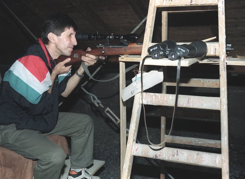 A Bosnian soldier takes aim through the telescope of his rifle from his position overlooking one of the Serb controlled areas of Sarajevo on September 11, 1992. REUTERS/Corinne Dufka