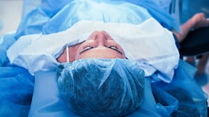 Young lady lying on the operation table with a surgical screen covering her body below the waist