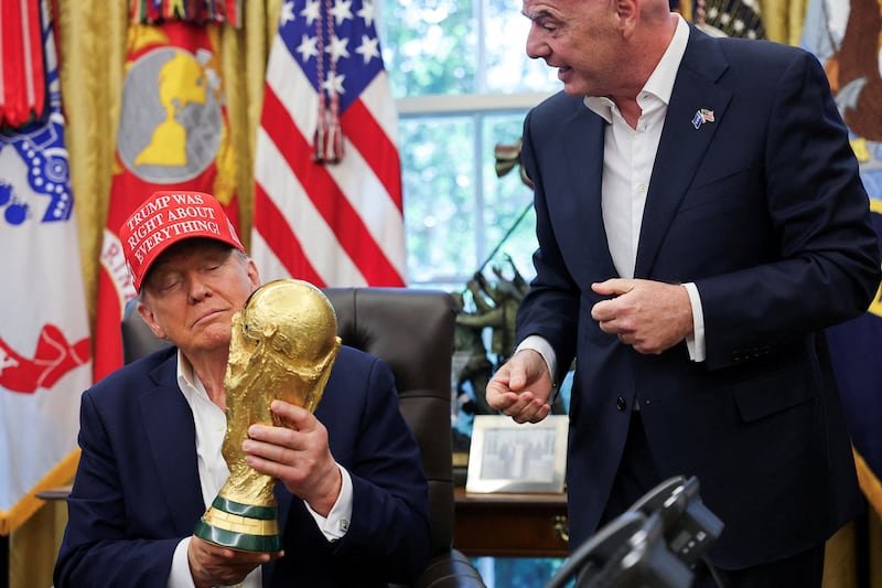 U.S. President Donald Trump holds the FIFA World Cup Trophy, as he makes an announcement on the 2026 FIFA World Cup, as FIFA president Gianni Infantino stands next to him, in the Oval Office at the White House in Washington, D.C., U.S., August 22, 2025.