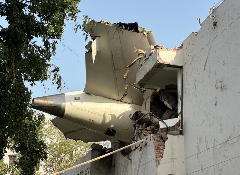 The tail of the aircraft was stuck on a building after the crash—students at a medical college hit by the plane were among those killed.