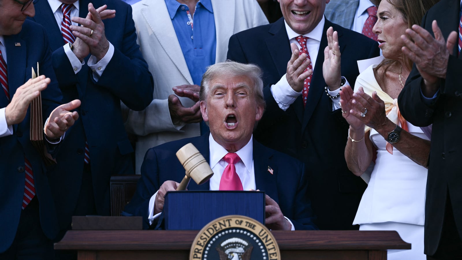 US President Donald Trump (C) holds a gavel after signing the "Big Beautiful Bill Act" at the White House in Washington, DC, on July 4, 2025. US President Donald Trump signed his flagship tax and spending bill on July 4 in a pomp-laden Independence Day ceremony featuring fireworks and a flypast by the type of stealth bomber that bombed Iran. Trump pushed Republican lawmakers to get his unpopular "One Big Beautiful Bill" through a reluctant Congress in time for him to sign it into law on the US national holiday -- and they did so with a day to spare Thursday. (Photo by Brendan SMIALOWSKI / POOL / AFP) (Photo by BRENDAN SMIALOWSKI/POOL/AFP via Getty Images)