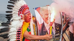 A shamans holds an image of US President Donald Trump during an end-of-year ritual in front of the sea in Chorrillos, Lima province, Peru, on December 29, 2025. (Photo by Connie FRANCE / AFP via Getty Images)