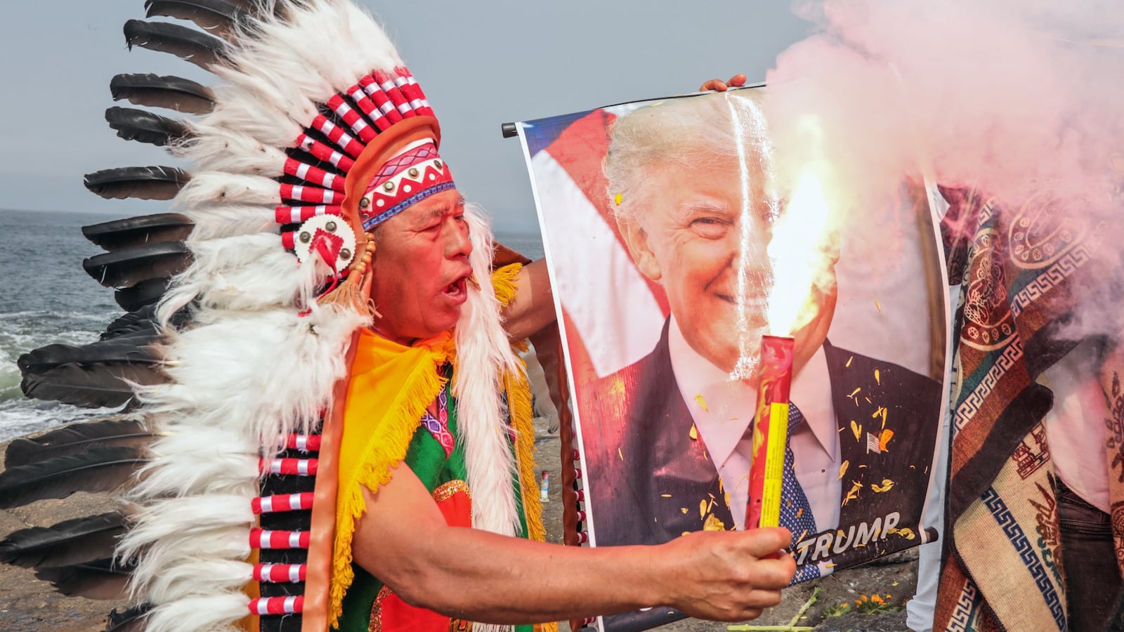 A shamans holds an image of US President Donald Trump during an end-of-year ritual in front of the sea in Chorrillos, Lima province, Peru, on December 29, 2025. (Photo by Connie FRANCE / AFP via Getty Images)