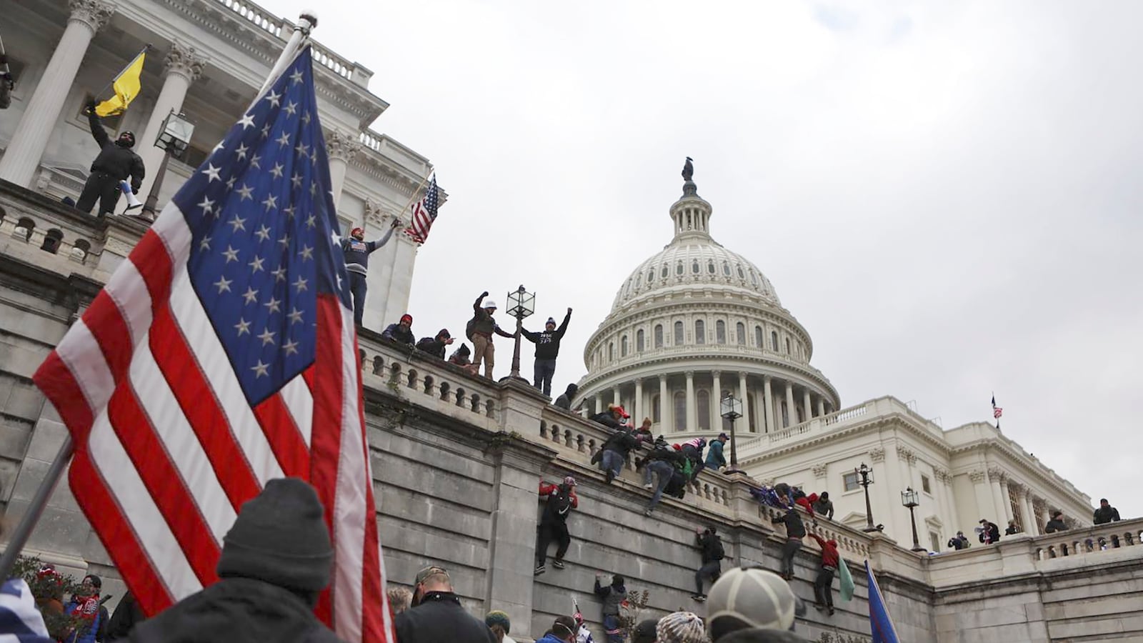 Supporters of U.S. President Donald Trump scale the walls of the U.S. Capitol Building.