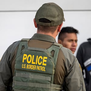 EAGLE PASS, TEXAS - JANUARY 07: A U.S. Border Patrol agent watches as immigrants prepare to board a bus after crossing the U.S.-Mexico border on January 07, 2024 in Eagle Pass, Texas. According the a new report released by U.S. Department of Homeland Security, some 2.3 million migrants, mostly from families seeking asylum, have been released into the U.S. under the Biden Administration since 2021. (Photo by John Moore/Getty Images)
