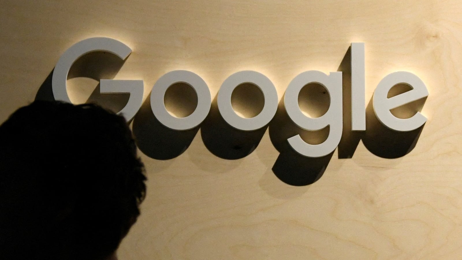 A woman passes the logo from the web search engine provider Google