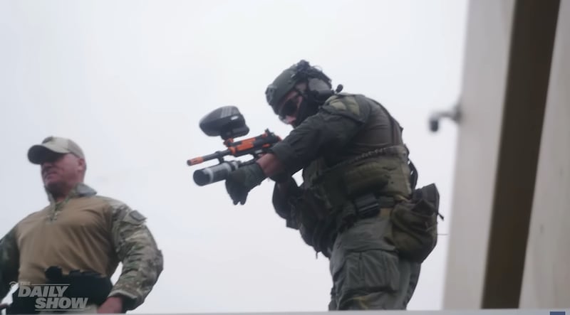 The Daily Show, shot of agent shooting what appears to be pepper bullets at protesters.