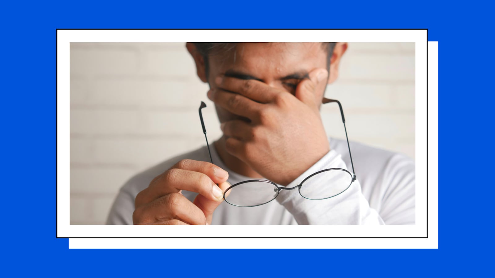 Tired man takes off his glasses to rub his eyes.