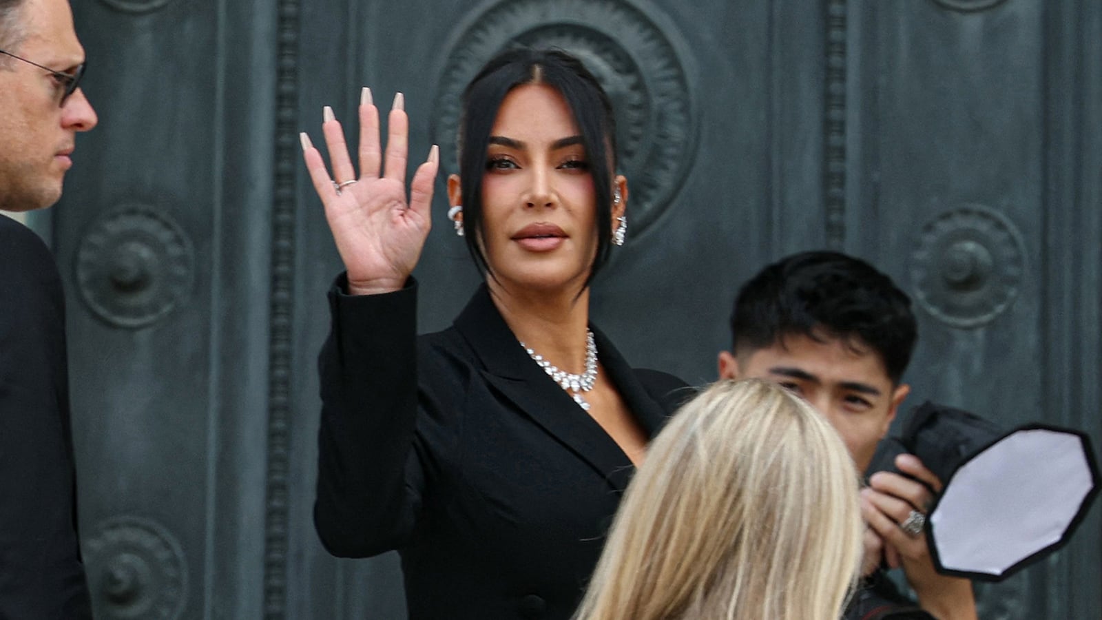 TOPSHOT - US celebrity Kim Kardashian (C) waves as she arrives at the Assize Court for the trial during which she will testify over the 2016 robbery that saw her relieved of millions of dollars' worth of jewellery at gunpoint in Paris, on May 13, 2025. The trial of this sensational nine million euro jewellery robbery opened in Paris on April 28, 2025. (Photo by Alain JOCARD / AFP) (Photo by ALAIN JOCARD/AFP via Getty Images)
