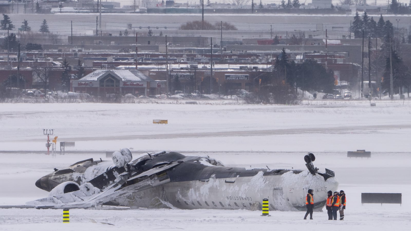 Airport workers survey the site of a Delta Air Lines plane crash that injured at least 18 passengers at Toronto Pearson International Airport on February 18, 2025 in Toronto, Canada.