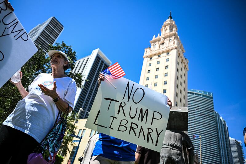 Protesters hold signs as they protest opposing plans to build a Trump library near Miami's Freedom Tower in Miami.