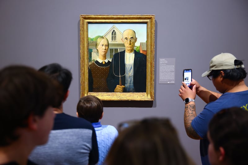 Visitors contemplate 'American Gothic' painting by Grant Wood