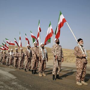 Members of the Islamic Revolutionary Guard Corps (IRGC) stand in a row carrying flags at a military drill
