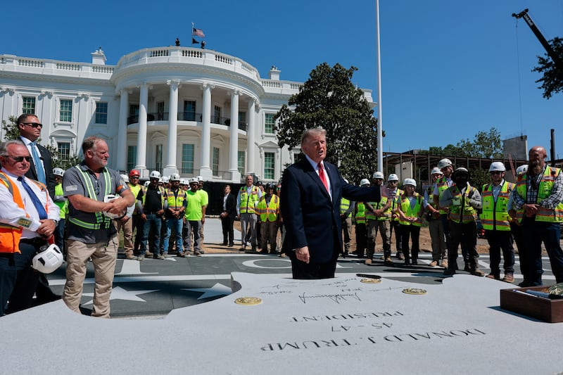 President Donald Trump gestures, after signing a stone that will be inserted into the helipad being constructed on the South Lawn, at the White House on August 19, 2026.