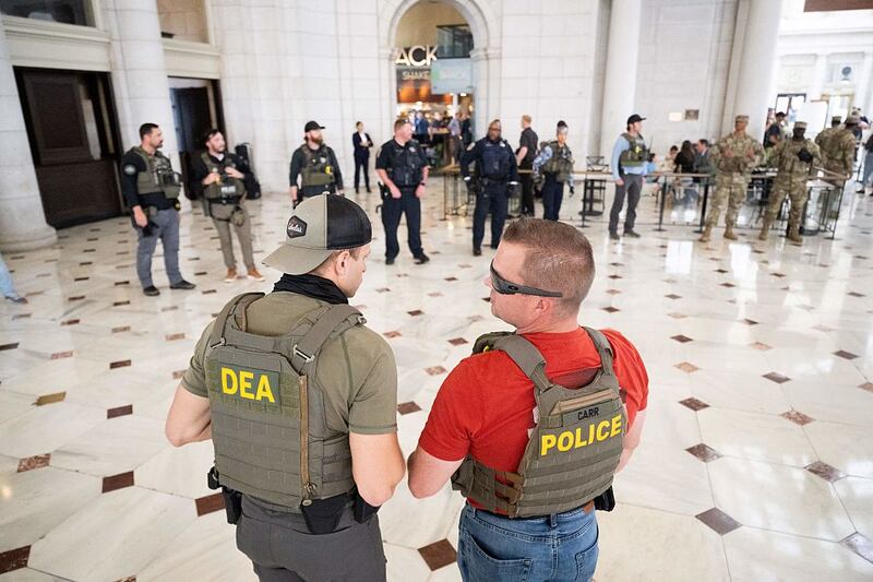 Law enforcement officials stand guard outside of Shake Shack while US Vice President JD Vance, Defense Secretary Pete Hegseth and White House Deputy Chief of Staff Stephen Miller (not pictured) visit with members of the National Guard stationed at Union Station in Washington, DC, on August 20, 2025. US President Donald Trump on August 11 deployed military and federal law enforcement to curb violent crime in Washington, as he seeks to make good on his campaign pledge to be a "law and order" president. The Republican leader said he would place the city's Metropolitan Police under federal government control while also sending the National Guard onto the streets of the US capital. (Photo by SAUL LOEB / AFP) (Photo by SAUL LOEB/AFP via Getty Images)