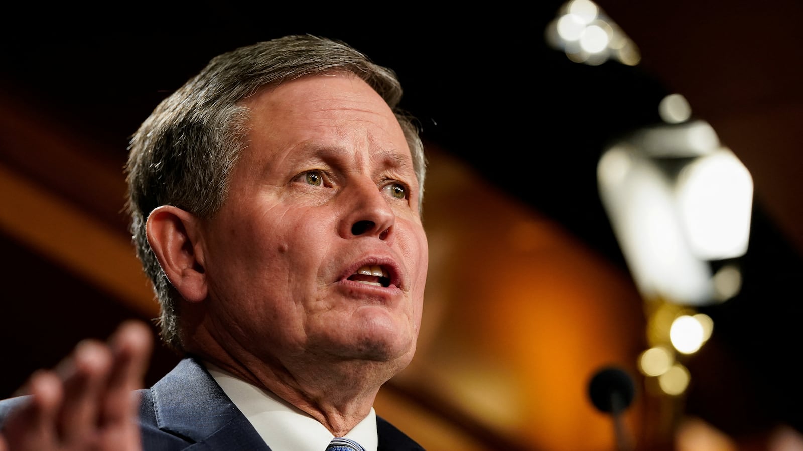 Senator Steve Daines speaking at a microphone.