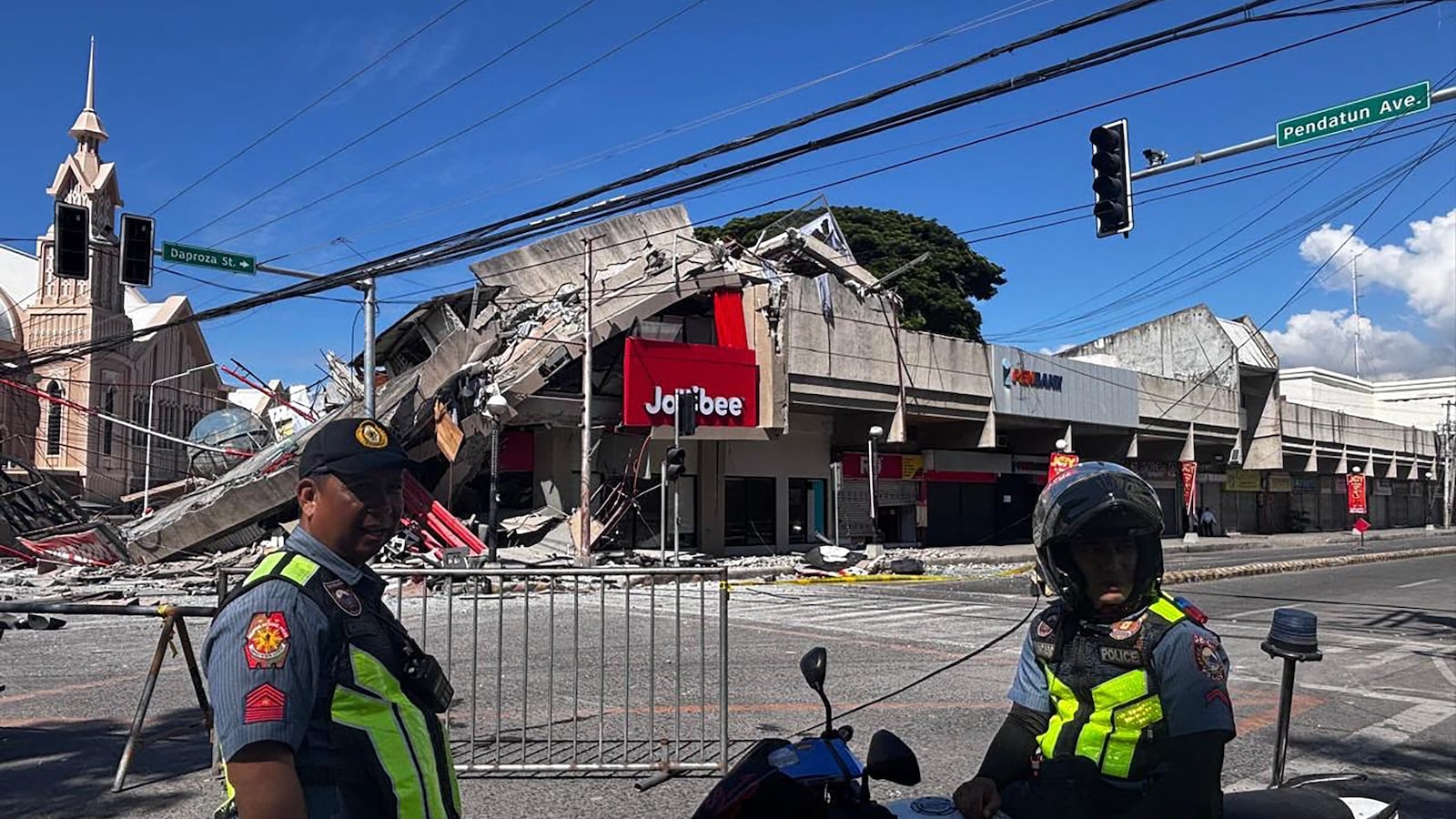 TOPSHOT - Police gather in front of a collapsed Jollibee fast food restaurant after an 7.8 magnitude earthquake in General Santos City on June 8, 2026. A 7.8-magnitude earthquake that struck the southern Philippines on June 8 killed at least one person and collapsed buildings, police said, as the disaster sparked tsunami warnings across the region. (Photo by Edwin Espejo / AFP via Getty Images)