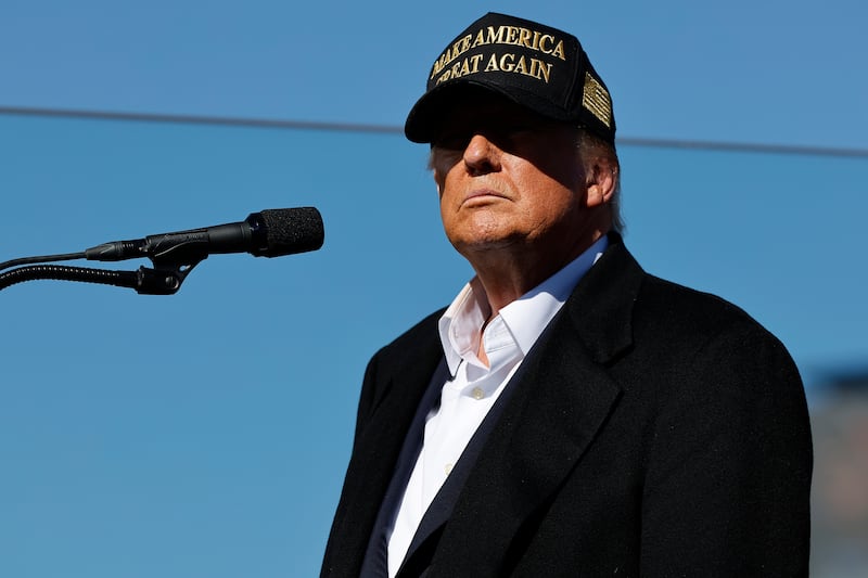 Trump in a black-and-gold MAGA hat.