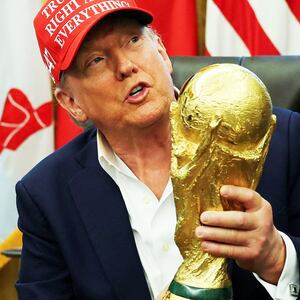 President Donald Trump wears a 'Trump Was Right About Everything!' hat while holding the FIFA World Cup Trophy, as he makes an announcement on the 2026 FIFA World Cup, in the Oval Office at the White House in Washington, D.C., U.S., August 22, 2025.