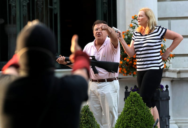 Mark and Patricia McCloskey stand in front their house along Portland Place as they confront protesters marching to St. Louis Mayor Lyda Krewson's house Sunday, June 28, 2020, in the Central West End of St. Louis.