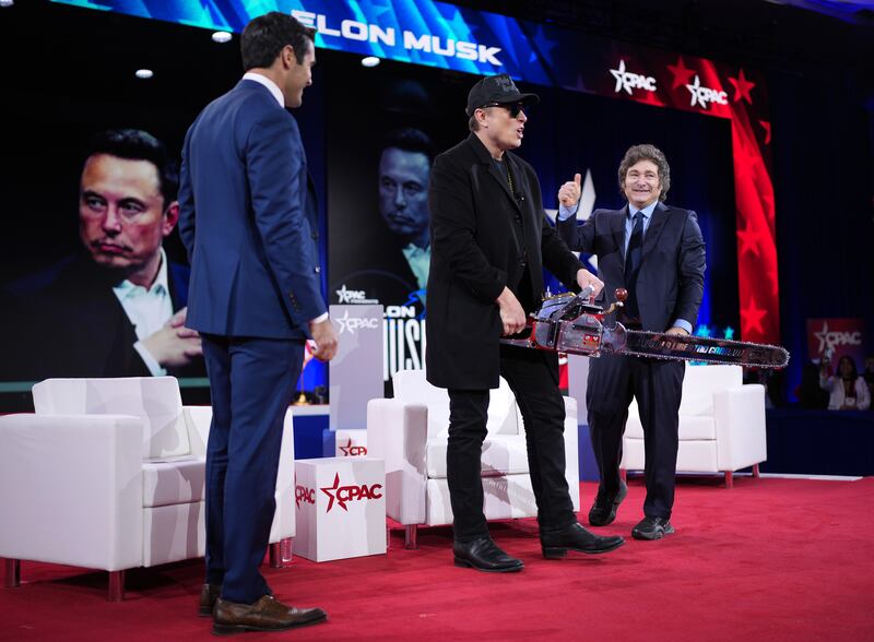 OXON HILL, MARYLAND - FEBRUARY 20: CEO of Tesla and SpaceX Elon Musk holds a chainsaw as he arrives on stage at the Conservative Political Action Conference (CPAC) at the Gaylord National Resort Hotel And Convention Center on February 20, 2025 in Oxon Hill, Maryland. The annual four-day gathering brings together conservative U.S. lawmakers, international leaders, media personalities and businessmen to discuss and champion conservative ideas. Musk was joined on stage by Argentine President Javier Milei, who gifted Musk the chainsaw he used as a prop while campaigning. (Photo by Andrew Harnik/Getty Images)