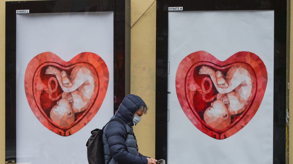 Two billboards with images of a fetus inside a heart shaped womb.