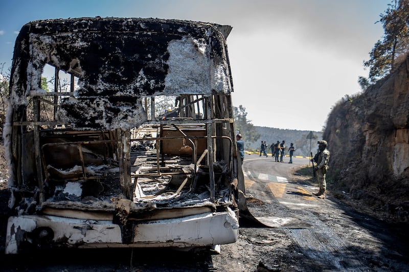 Members of the Mexican National Guard and Army inspect vehicles allegedly set on fire by members of organized crime on the road between Morelia and Patzcuaro, Michoacan state, Mexico on February 22, 2026