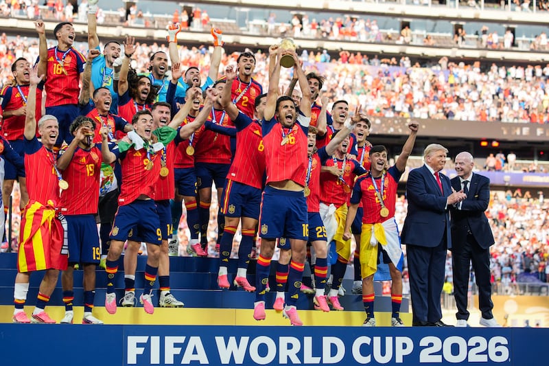 EAST RUTHERFORD, NEW JERSEY - JULY 19: US President Donald Trump and FIFA President Gianni Infantino stand on stage as Rodri #9 of Spain raises the FIFA World Cup Winner’s Trophy with his teammates after they defeated Argentina in the FIFA World Cup 2026 Final at New York New Jersey Stadium on July 19, 2026 in East Rutherford, New Jersey. Spain defeated reigning World Cup champions Argentina, who were led by Lionel Messi, with the lone goal coming from Ferran Torres #7 in the 106th minute of extra time. (Photo by Andrew Harnik/Getty Images)