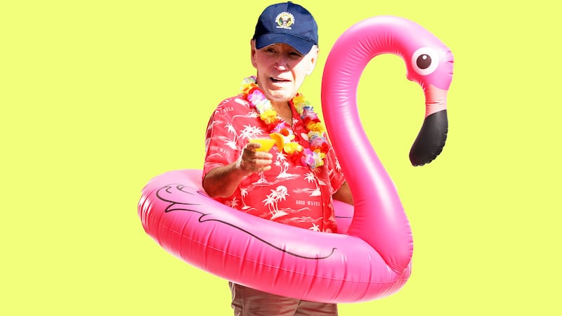 Joe Biden in a Hawaiin shirt holding a drink in a flamingo inflatable