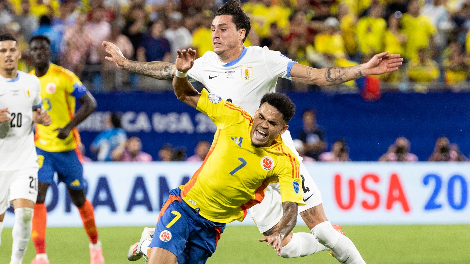 Luis Díaz #7 of Colombia and José Giménez #2 of Uruguay take a spill after a challenge during a game between Uruguay and Colombia at Bank of America Stadium on July 10, 2024 in Charlotte, North Carolina.