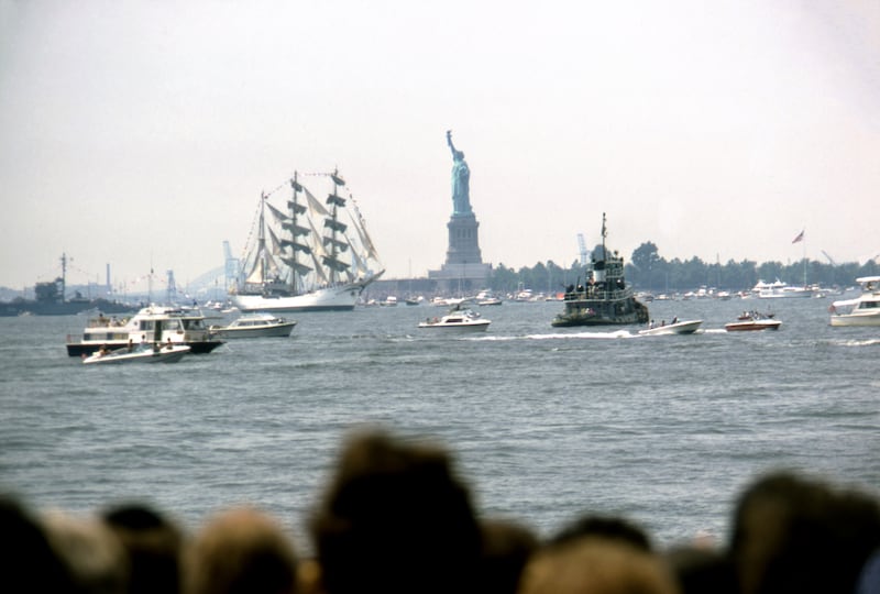 Spectators watch Operation Sail, a parade of 16 majestic tall ships from 14 nations to celebrate the United States Bicentennial, near the Statue of Liberty in New York Harbor. Taken on July 4, 1976 in New York City, New York.