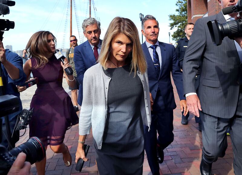 Lori Loughlin, center, and her husband Mossimo Giannulli, behind her at right, leave the John Joseph Moakley United States Courthouse in Boston on Aug. 27, 2019. A judge says actress Lori Loughlin and her fashion designer husband, Mossimo Giannulli, can continue using a law firm that recently represented the University of Southern California. The couple appeared in Boston federal court on Tuesday to settle a dispute over their choice of lawyers in a sweeping college admissions bribery case. Prosecutors had said their lawyers pose a potential conflict of interest. Loughlin and Giannulli say the firms work for USC was unrelated to the admissions case and was handled by different lawyers. (Photo by John Tlumacki/The Boston Globe via Getty Images)