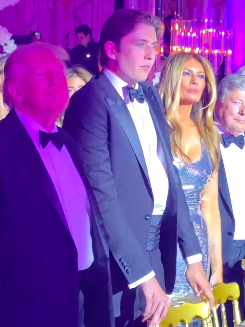 Barron Trump stands between his president after, Donald, and FLOTUS's mother, Melania, at the New Year's party at Mar-a-Lago.