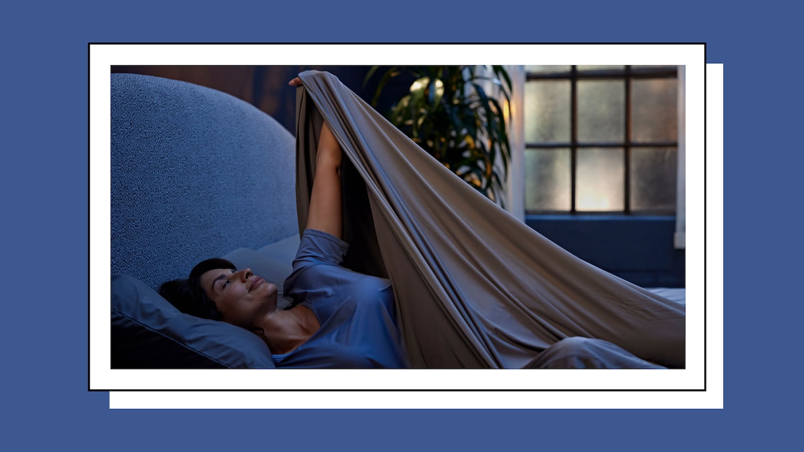 Woman sleeping in a large bed with grey sheets.