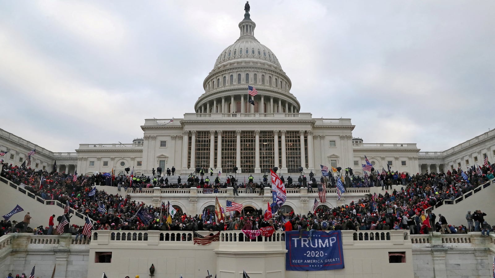 Rioting Trump supporters climb on the walls as they try to break in to the Capitol