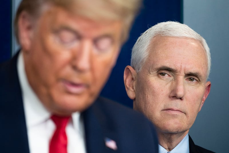 Mike Pence listens as Donald Trump speaks during a press briefing at the White House in Washington, DC, on March 26, 2020.