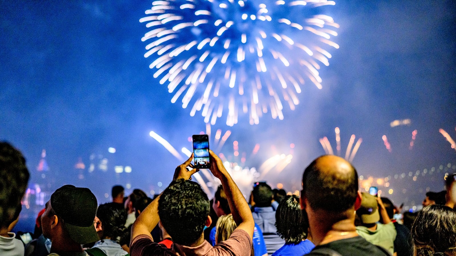 Spectators view (real) fireworks marking the July Fourth holiday at Brooklyn Bridge Park in New York City on July 4, 2025.