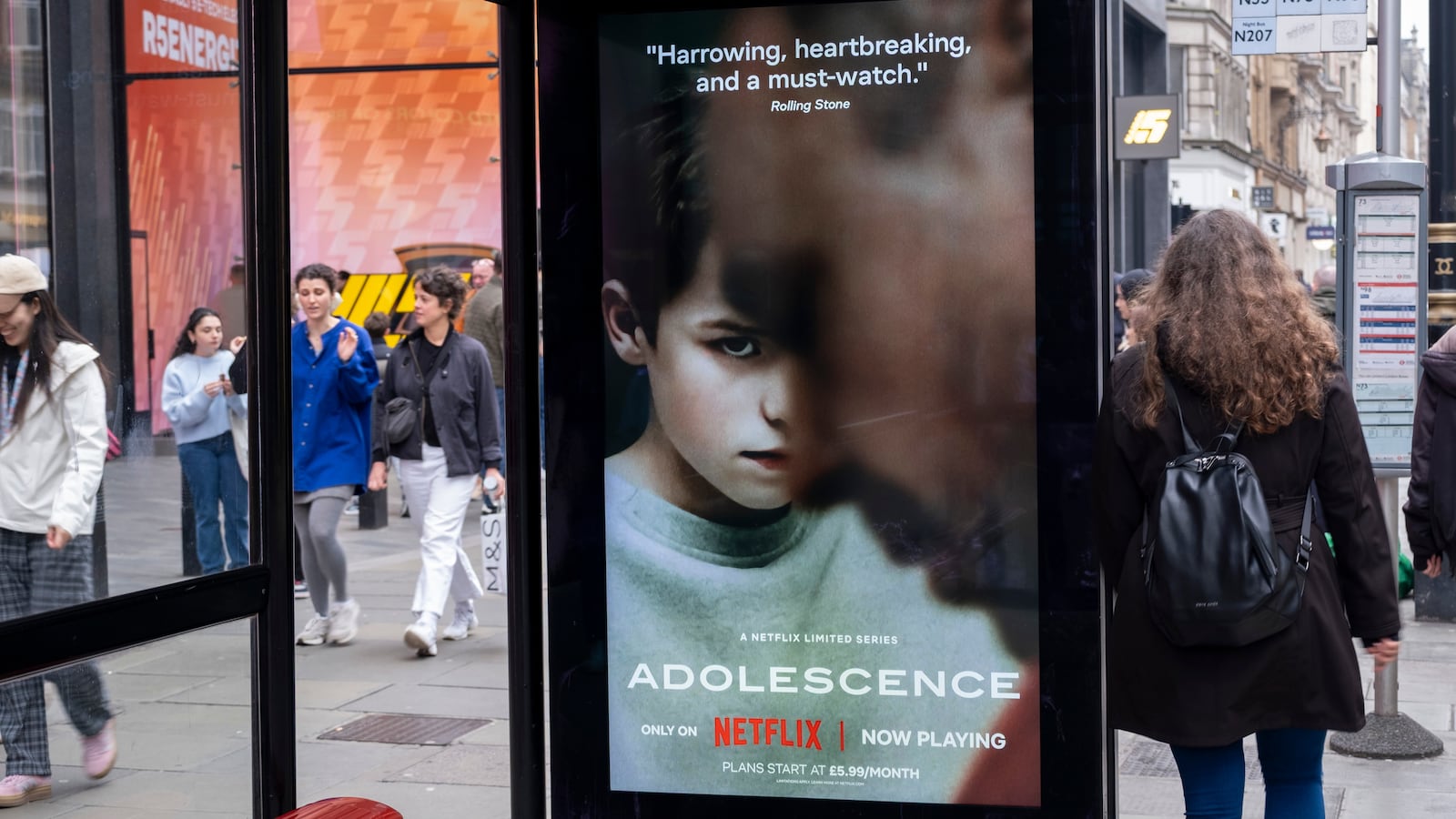 Passing people interacting with an advertising poster on a bus shelter for the Netflix drama 'Adolescence', the story of which is sparking conversations in public and government around the subject of toxic masculinity and children's access to dangerous and misogynistic content on the internet and social media on 23rd March 2025 in London, United Kingdom.