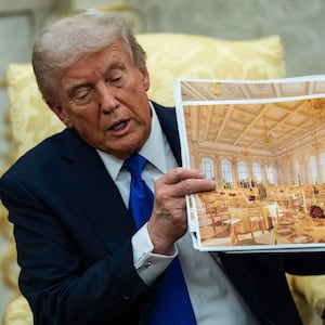 U.S. President Donald Trump speaks holding a photos of the new ballroom