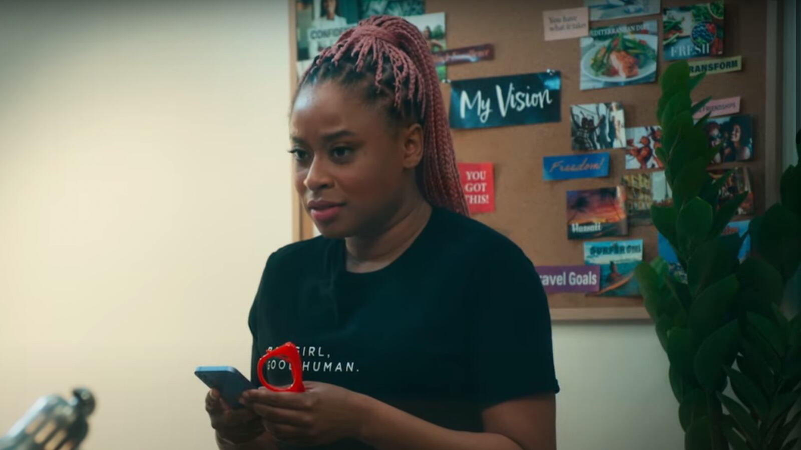 A woman with pink braids looks up from her cell phone.