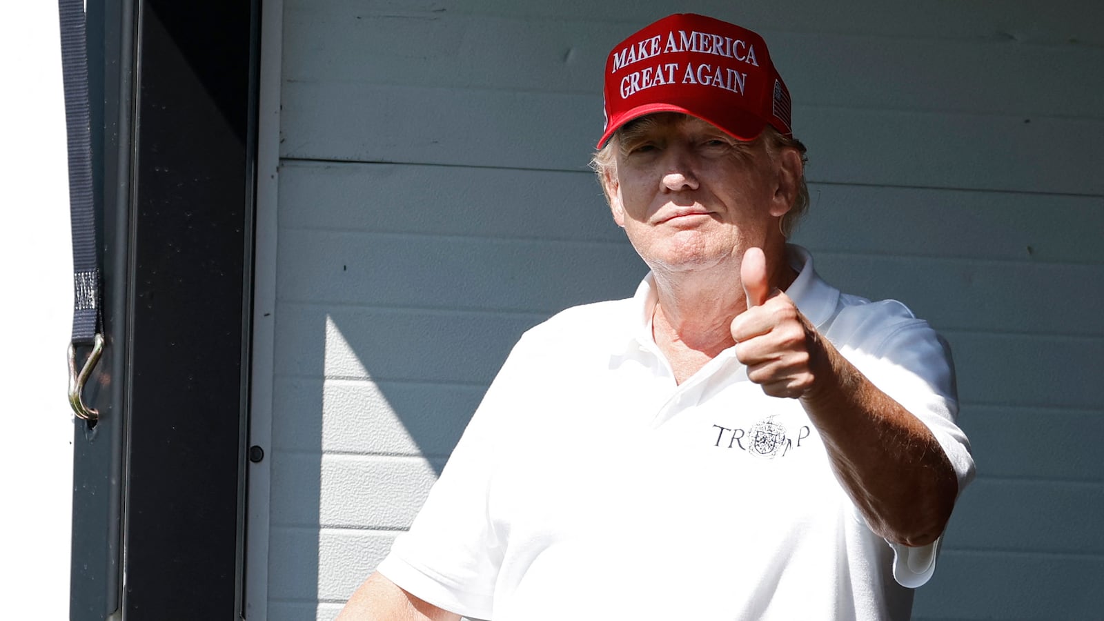 Former President Donald Trump gestures to fans from a hospitality suite on the eighteenth green during the first round of the LIV Golf DC 2023 tournament at Trump National Golf Club in Sterling, Va.